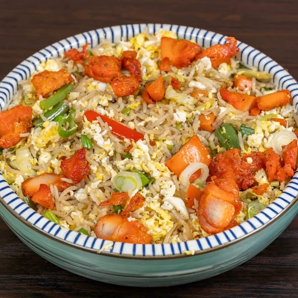 Biryani Pot's chicken fried rice with red chicken pieces, scrambled egg, and vegetables in a striped bowl.